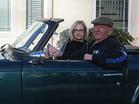 A photo of Maureen and David Wadiak sitting in their convertible.