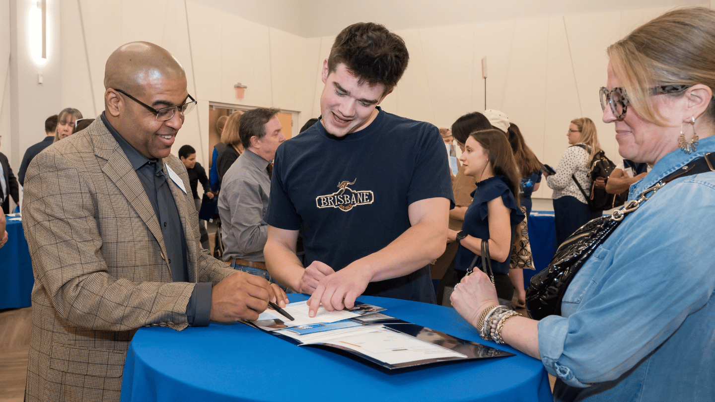 Student signing a document during open house