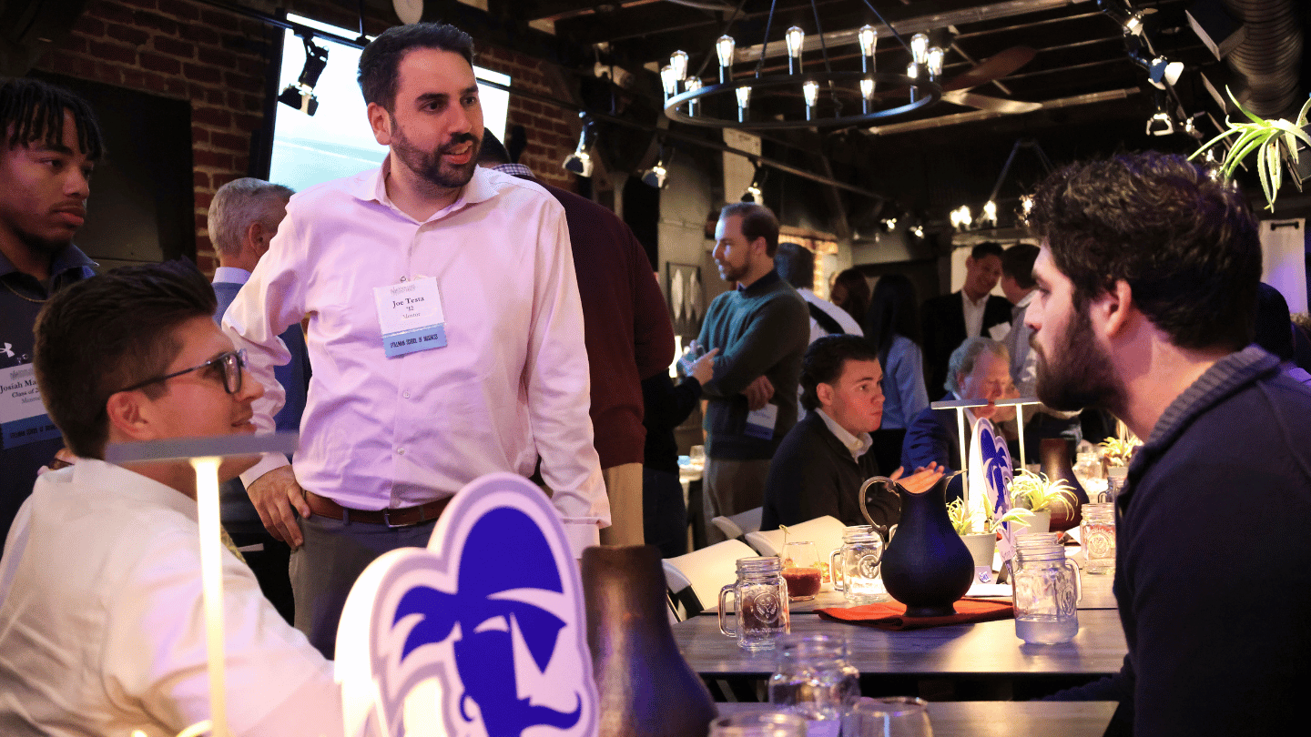 Picture of a Seton Hall mentor talking to two students at a resturant