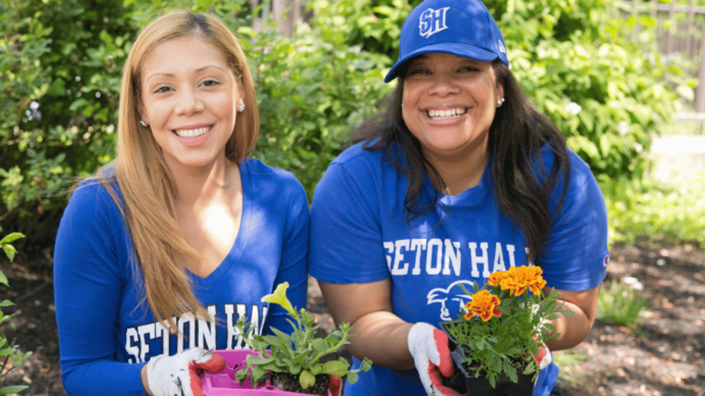 Two women pictured with plants in hand during a volunteer event