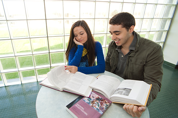 Two students looking at Philosophy texts in a lounge at Seton Hall.