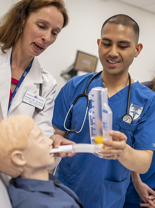 A nursing student with a professor learning how to administer a breathing treatment.